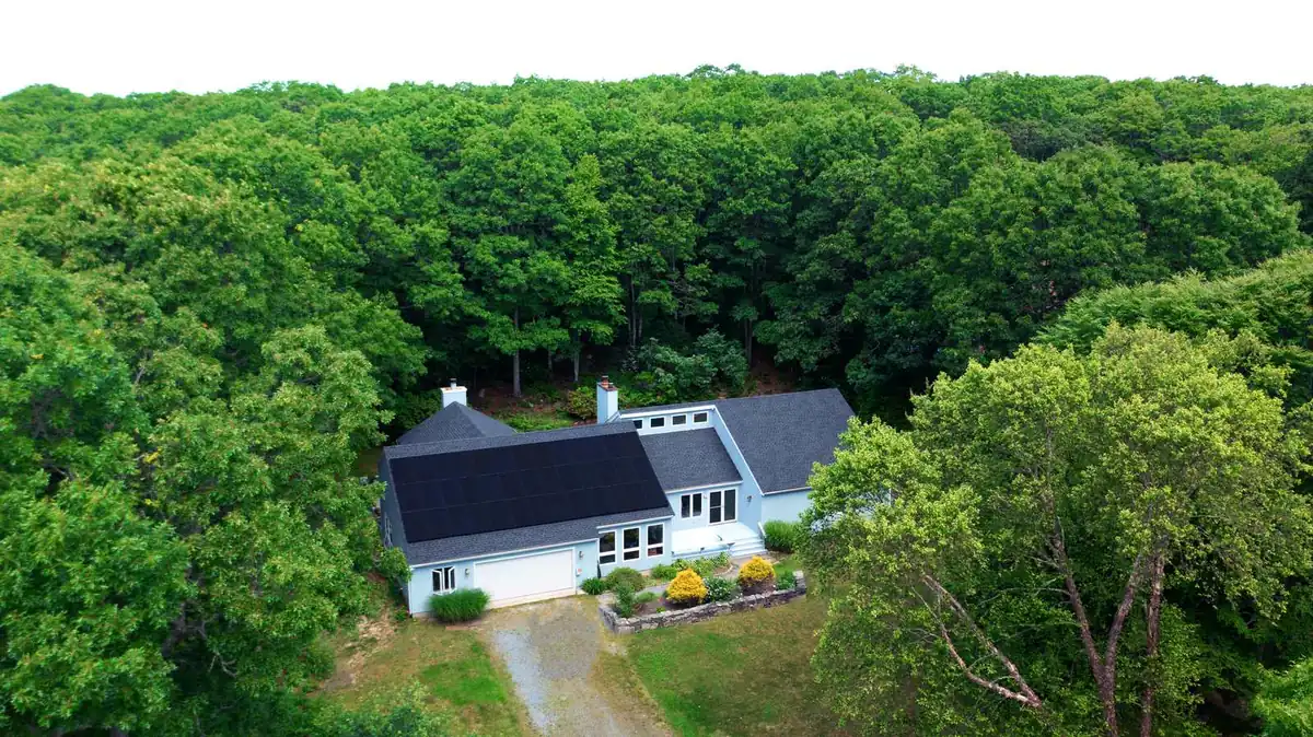 Aerial view of a cape-style home with black solar panels